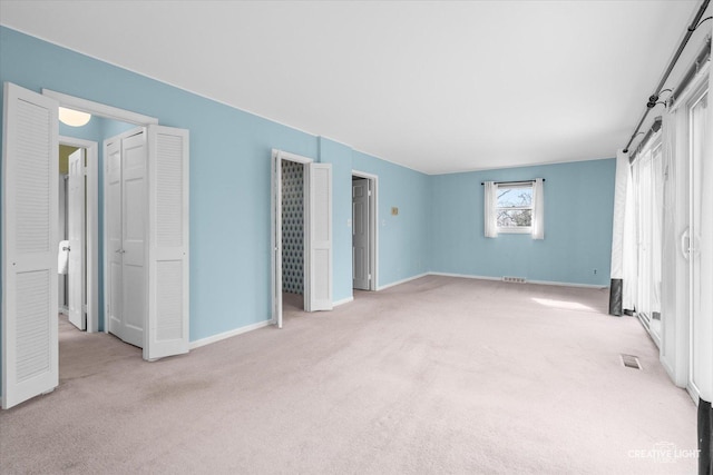 unfurnished bedroom with baseboards, visible vents, and light colored carpet