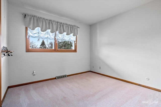 spare room with carpet, visible vents, and baseboards