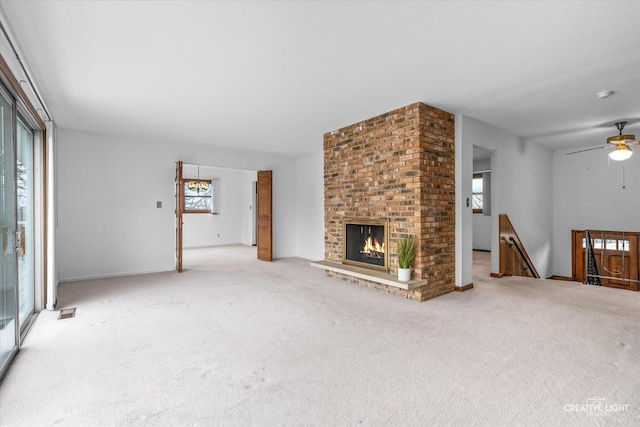 unfurnished living room featuring a ceiling fan, a brick fireplace, and light carpet