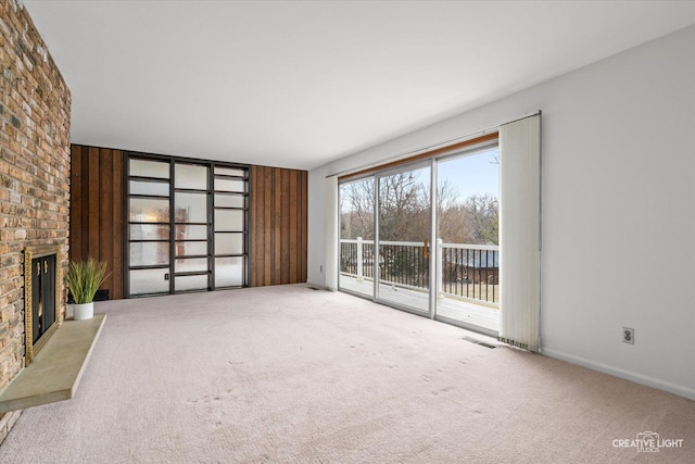 unfurnished living room with a brick fireplace, carpet flooring, and visible vents