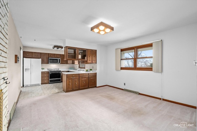 kitchen featuring light carpet, visible vents, light countertops, appliances with stainless steel finishes, and glass insert cabinets