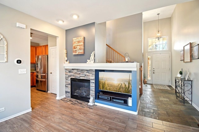 unfurnished living room featuring a chandelier, a fireplace, wood finished floors, and baseboards