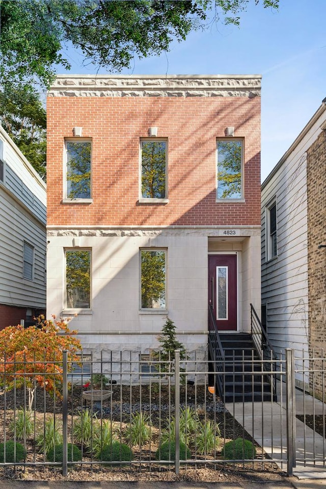 view of front of home with entry steps, a fenced front yard, and brick siding