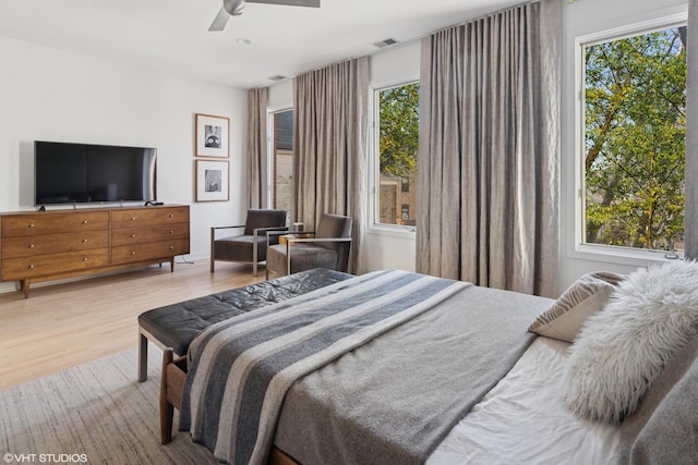 bedroom with ceiling fan, multiple windows, wood finished floors, and visible vents