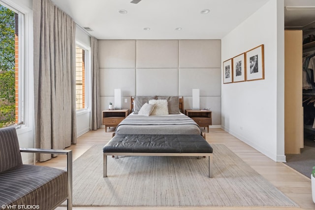 bedroom featuring baseboards, visible vents, a walk in closet, light wood-style floors, and a closet