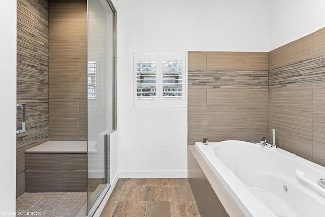 full bath featuring baseboards, a tub with jets, and a shower stall