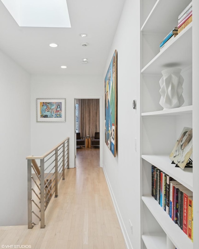 corridor featuring built in shelves, a skylight, recessed lighting, an upstairs landing, and wood finished floors