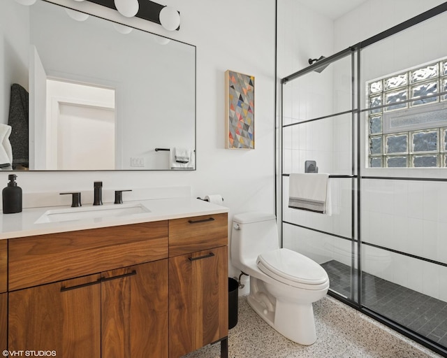 bathroom featuring vanity, a shower stall, toilet, and speckled floor