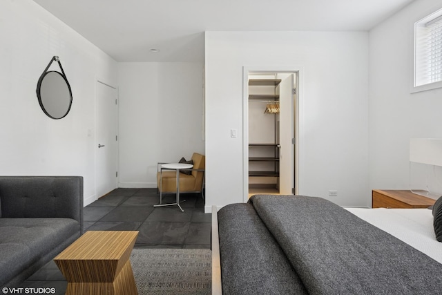 bedroom featuring a walk in closet and baseboards