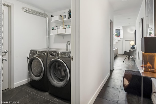 laundry room with baseboards, dark tile patterned floors, and washing machine and clothes dryer