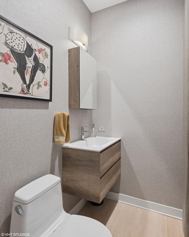 bathroom featuring baseboards, vanity, toilet, and wood finished floors