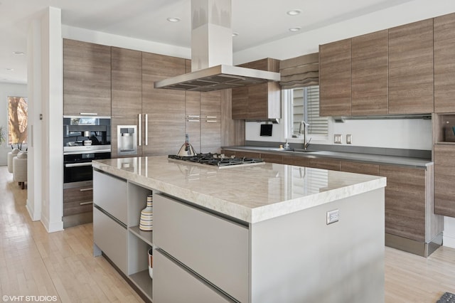 kitchen with light wood-style flooring, modern cabinets, a center island, island exhaust hood, and a sink