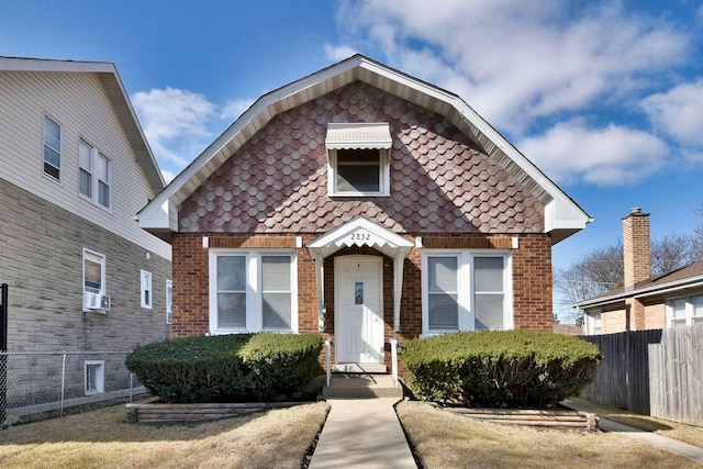 view of front of house with cooling unit, brick siding, and fence