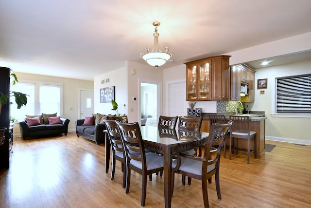 dining area featuring light wood-type flooring, visible vents, and baseboards