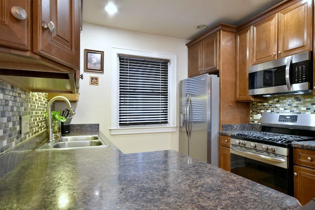 kitchen with stainless steel appliances, dark countertops, brown cabinets, and a sink