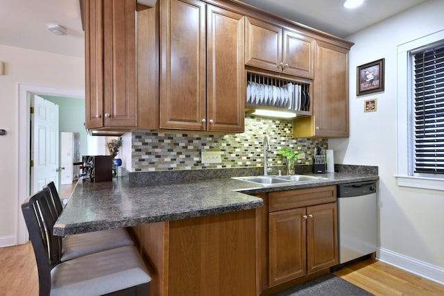 kitchen with a sink, dark countertops, tasteful backsplash, and dishwasher