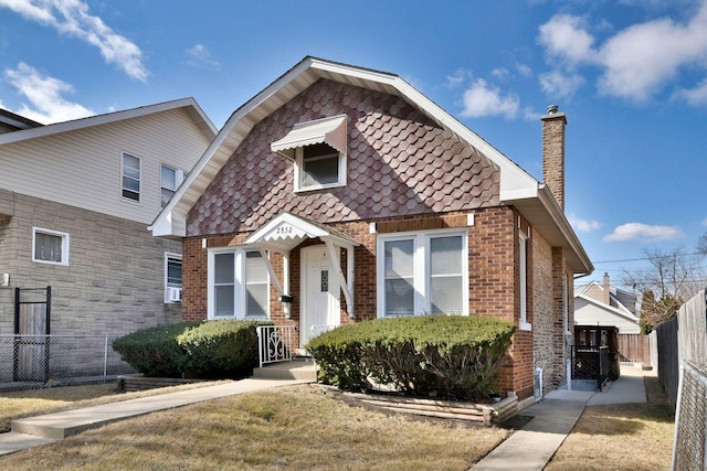 view of front of house featuring a chimney, fence, and brick siding