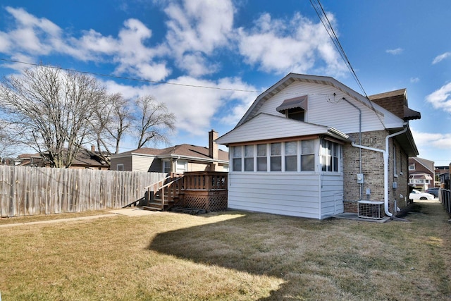 rear view of property featuring a yard, fence, a deck, and a gambrel roof