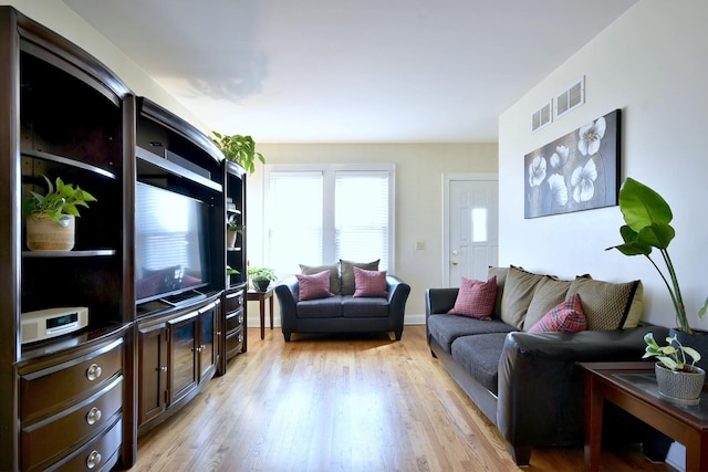 living room featuring light wood-type flooring, visible vents, and baseboards