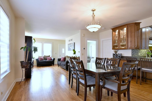 dining space featuring light wood-style floors, visible vents, and baseboards