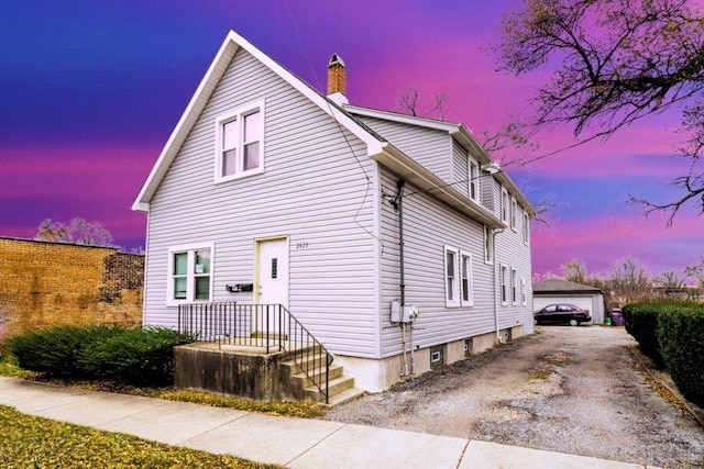 exterior space with a garage, an outbuilding, and a chimney