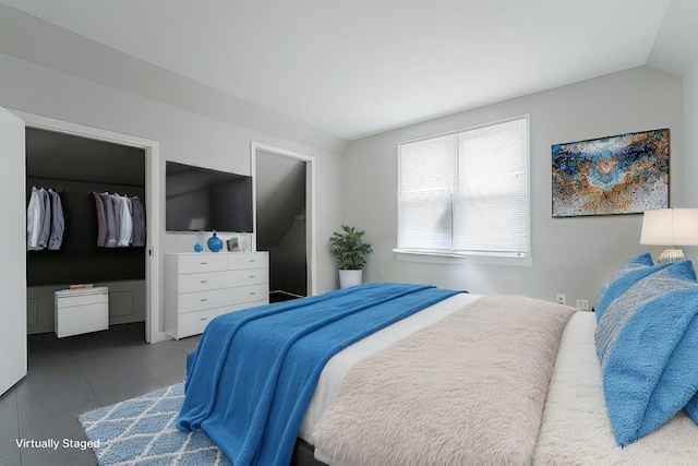 bedroom featuring a closet, vaulted ceiling, a spacious closet, and tile patterned floors