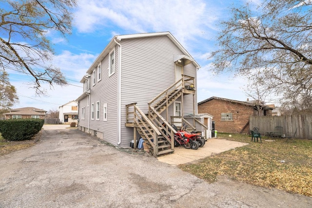 rear view of house featuring fence and stairway