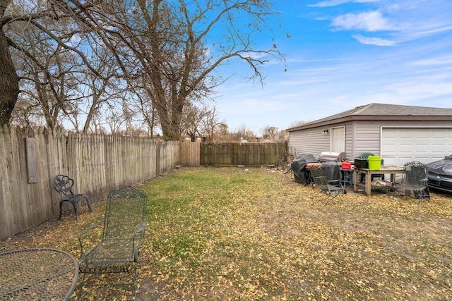 view of yard with a garage and a fenced backyard