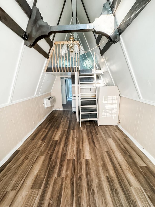 interior space featuring an AC wall unit, lofted ceiling with beams, and wood finished floors