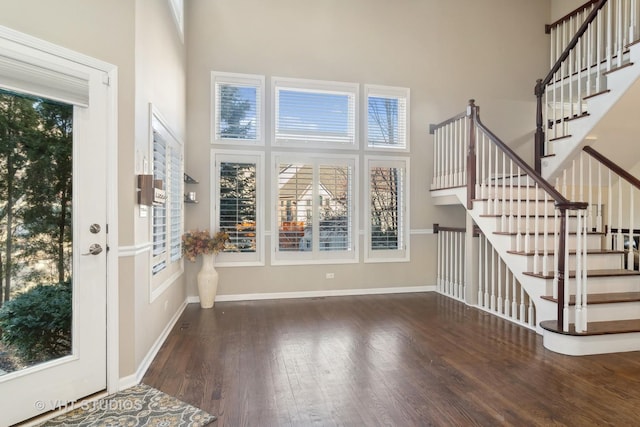 foyer entrance with stairs, baseboards, a high ceiling, and wood finished floors