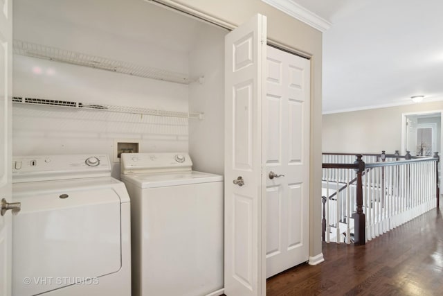 clothes washing area featuring laundry area, ornamental molding, washing machine and dryer, and dark wood finished floors