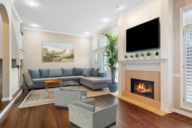 living area with ornamental molding, visible vents, a tiled fireplace, and wood finished floors