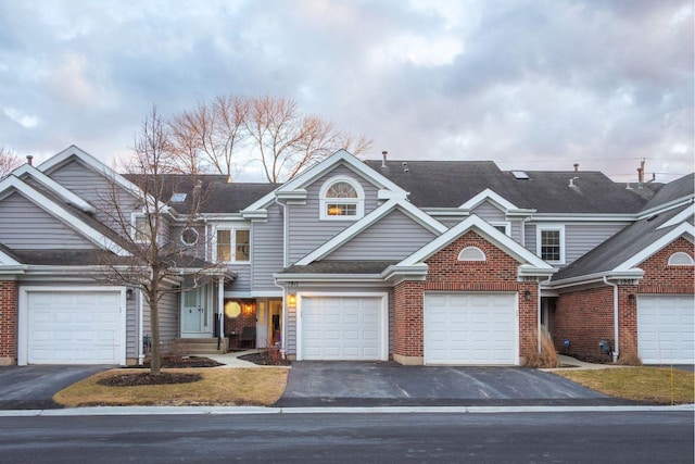 view of front of property with a garage, driveway, brick siding, and a shingled roof