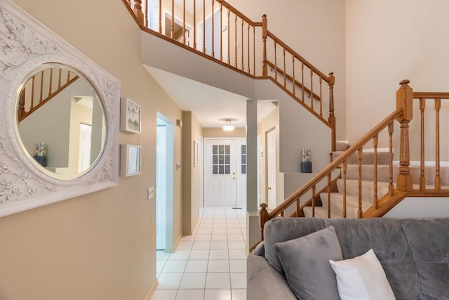 entryway with baseboards, stairway, a high ceiling, and light tile patterned floors