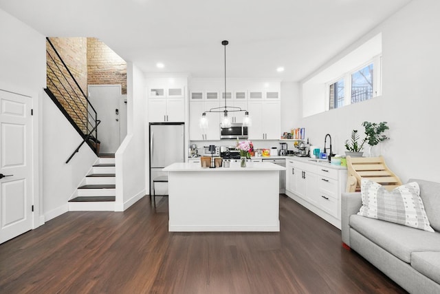 kitchen featuring decorative light fixtures, white cabinetry, light countertops, appliances with stainless steel finishes, and glass insert cabinets