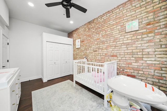 bedroom with dark wood finished floors, recessed lighting, a closet, brick wall, and baseboards