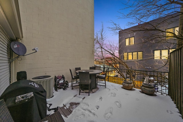 snow covered patio featuring central AC unit, area for grilling, and outdoor dining space