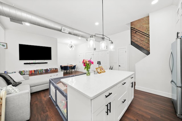 kitchen with a center island, decorative light fixtures, visible vents, freestanding refrigerator, and white cabinetry