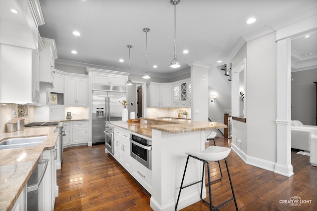 kitchen featuring a kitchen bar, ornamental molding, appliances with stainless steel finishes, and a sink