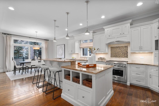 kitchen featuring dark wood-type flooring, white cabinets, high end stainless steel range oven, backsplash, and a center island