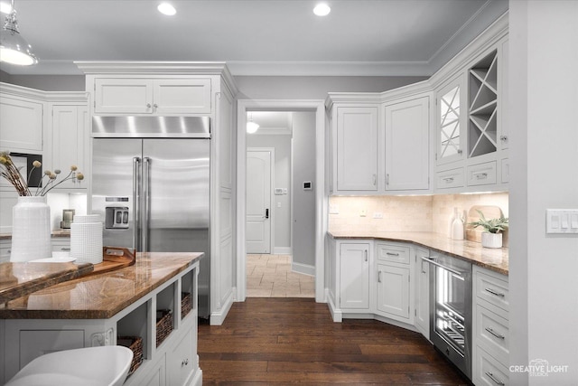 kitchen featuring beverage cooler, stainless steel built in refrigerator, light stone counters, backsplash, and white cabinetry