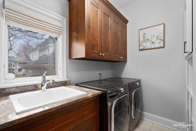 clothes washing area with light tile patterned floors, baseboards, cabinet space, a sink, and washer and clothes dryer