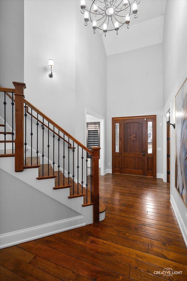 entryway featuring a high ceiling, stairs, baseboards, and hardwood / wood-style floors