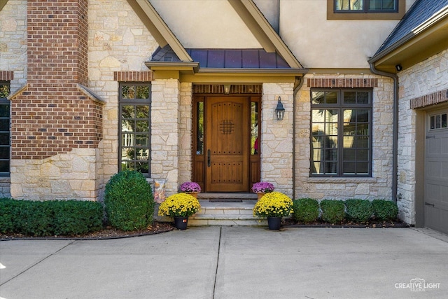 entrance to property featuring a standing seam roof, stucco siding, stone siding, and metal roof