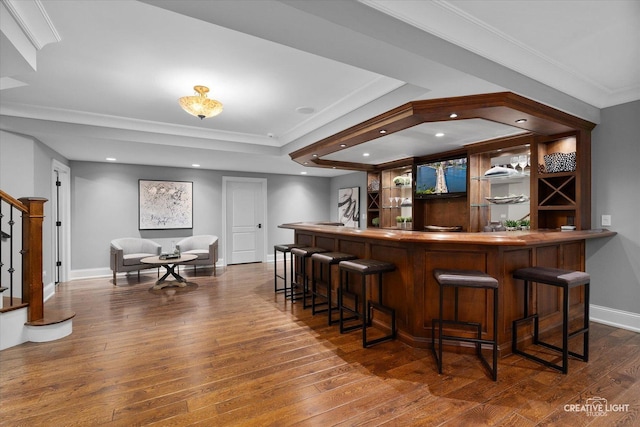 bar with baseboards, dark wood-style flooring, ornamental molding, indoor wet bar, and stairs