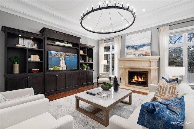 living area with an inviting chandelier, wood finished floors, a premium fireplace, and ornamental molding