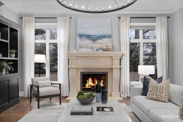 living room with a premium fireplace, an inviting chandelier, wood finished floors, and ornamental molding