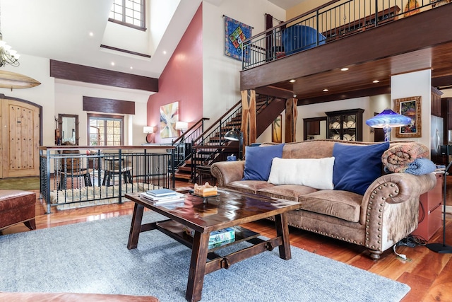 living area with stairs, a high ceiling, wood finished floors, and recessed lighting