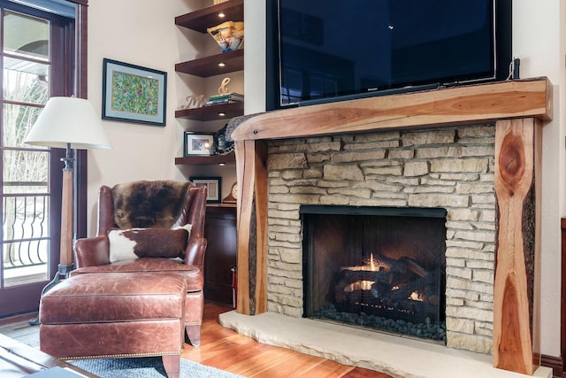 sitting room featuring a stone fireplace and wood finished floors