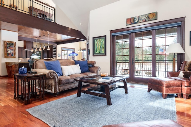 living area featuring high vaulted ceiling, wood finished floors, and a healthy amount of sunlight